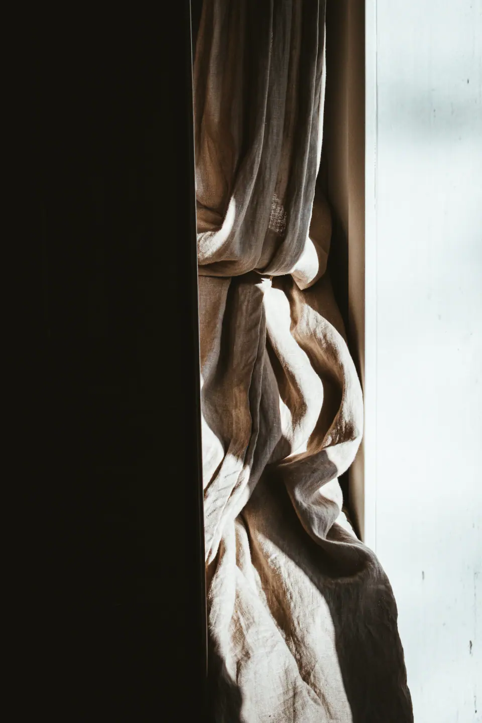 Sunlit folds of natural linen drapery